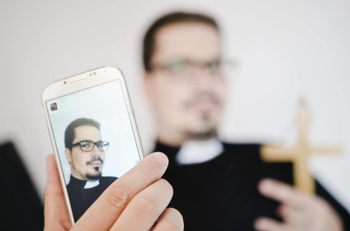 Priester hält Handy